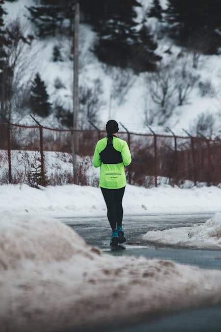 Person in winter clothing walking a narrow trail through a frost-covered forest at first light